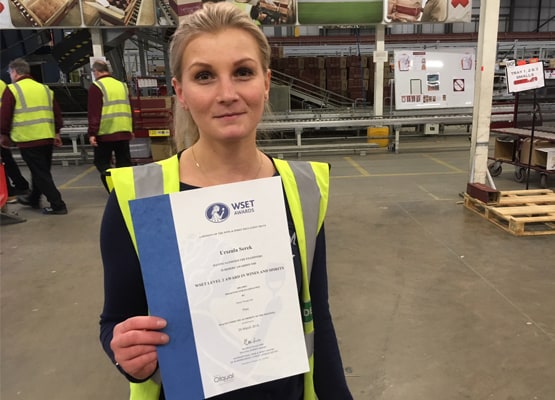 Lady in a warehouse holding her WSET Certificate
